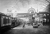 Railway staff look on as a boy holding his tedy bear waits to board his first steam train in around 1910 at New Street Station, Birmingham
